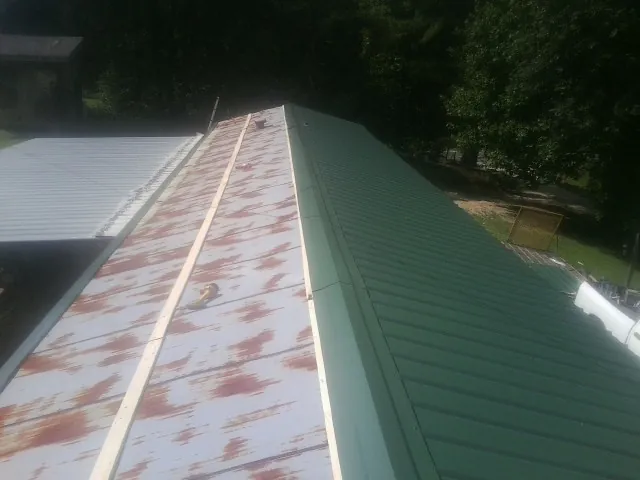 Old rusted panels beside newly installed green metal roofing — Wind Damage Roof Repair by Roofing Brothers in Prairie Lea