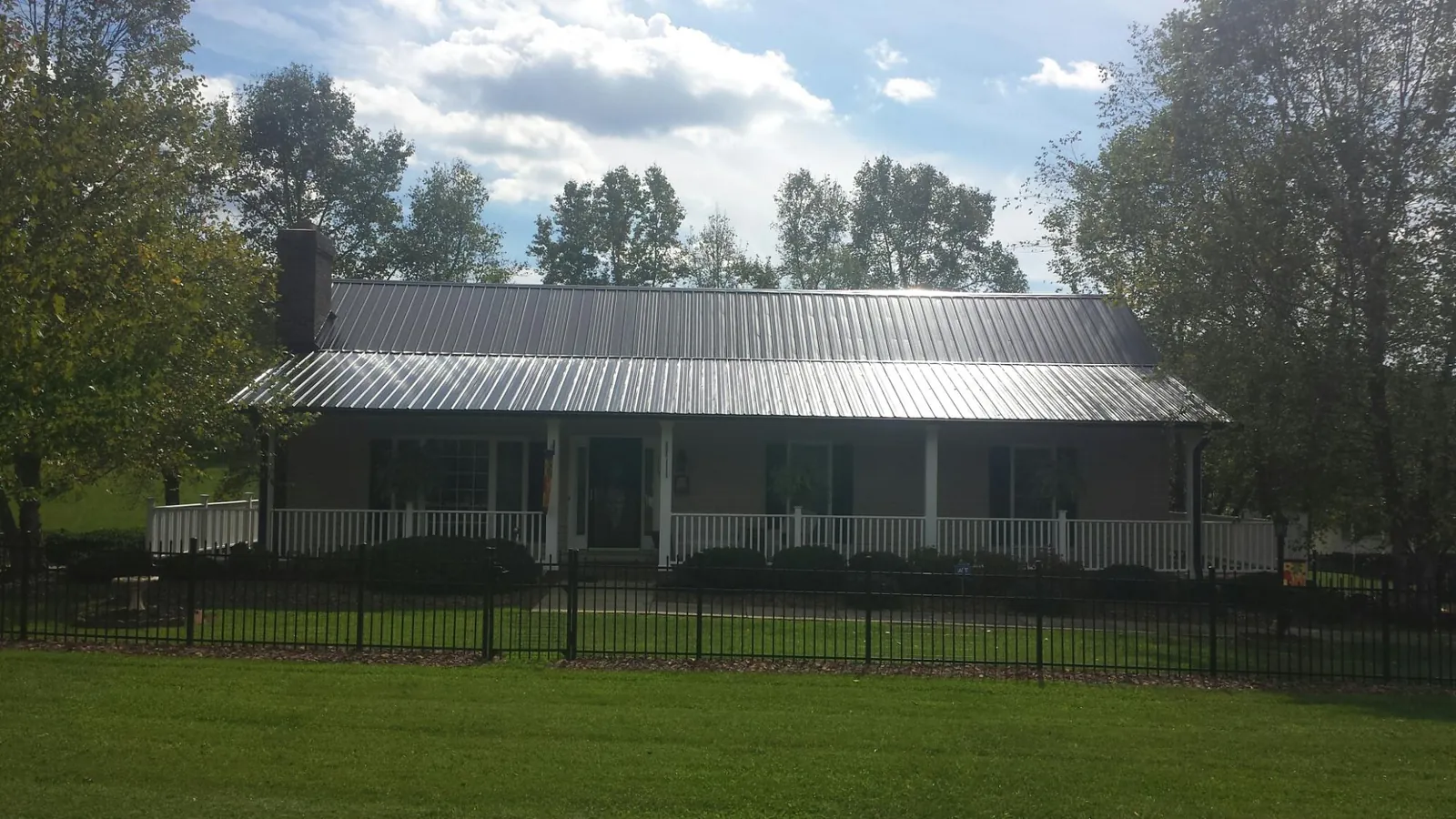 Gray metal roof on a brick ranch with a full width front porch — Gutter Guard Installation work by our crew in Prairie Lea