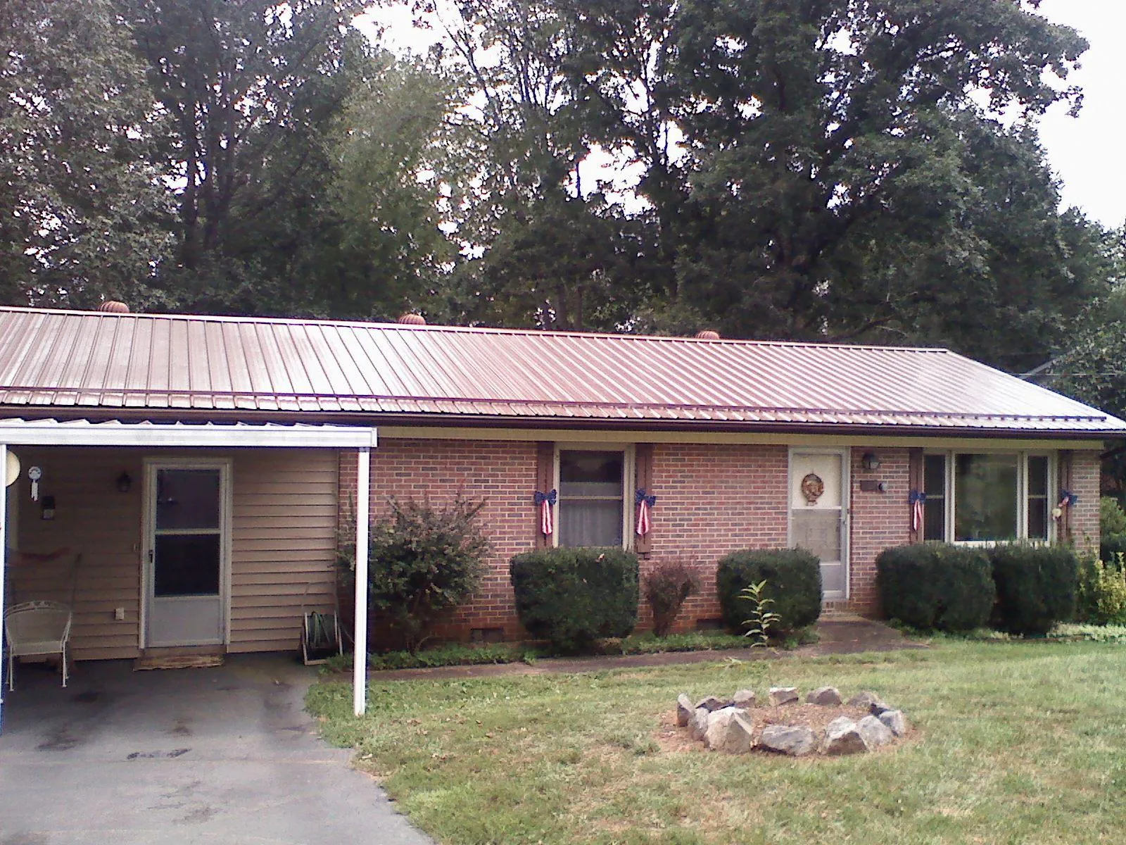 Bronze metal roof and carport on a brick ranch home — Roof Repair work by our crew in Prairie Lea