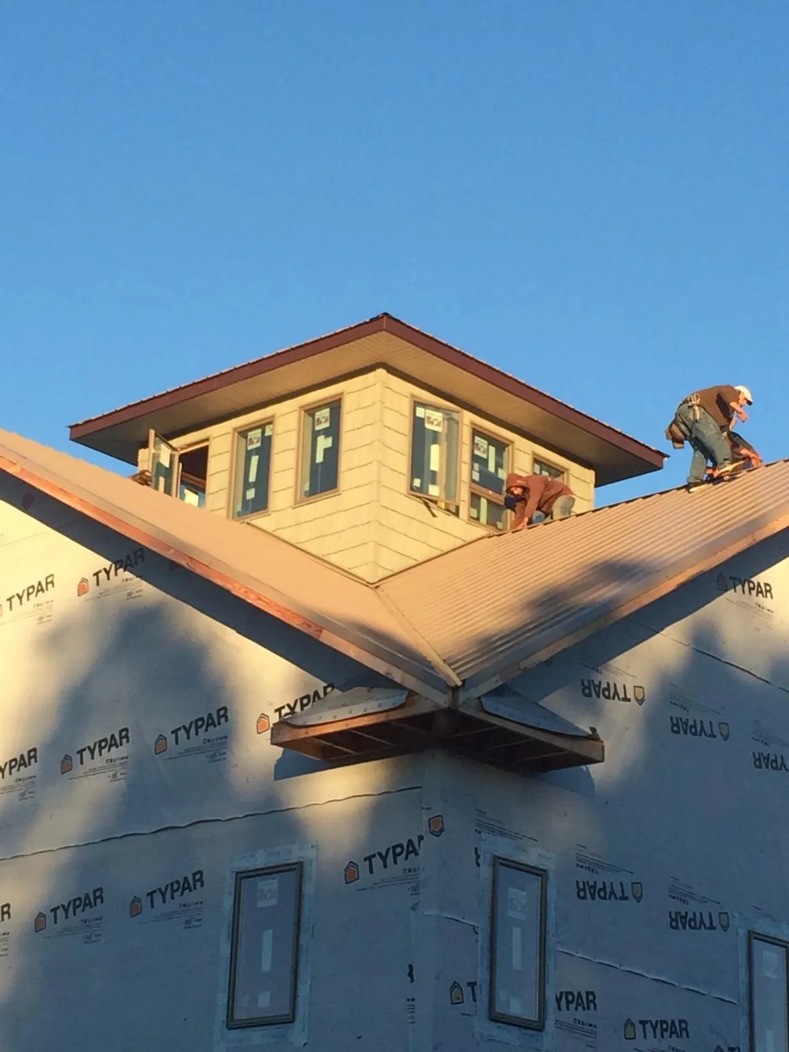 Roofers working around a rooftop cupola on a new metal roof at sunset — Roof Waterproofing in Prairie Lea by Roofing Brothers
